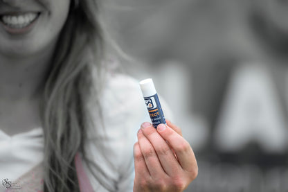 Woman outdoors holding a tube of Trail Armour PROTECT lip balm